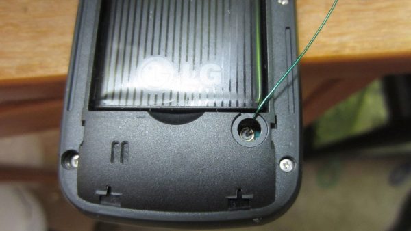 a LG brand phone opened at the back with a wire connected to it