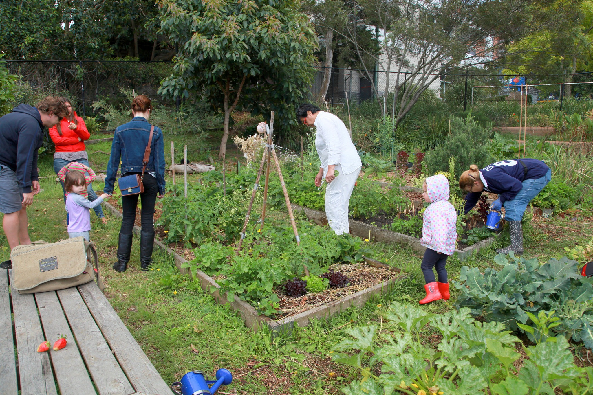 a group of people with their children working together to take care of the community garden