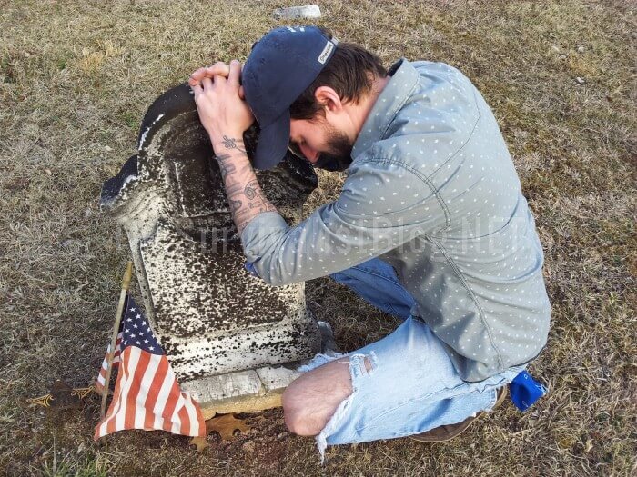 man kneeling next to tombstone