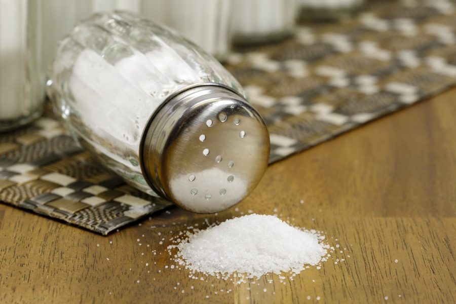 A salt shaker spilling salt onto a table
