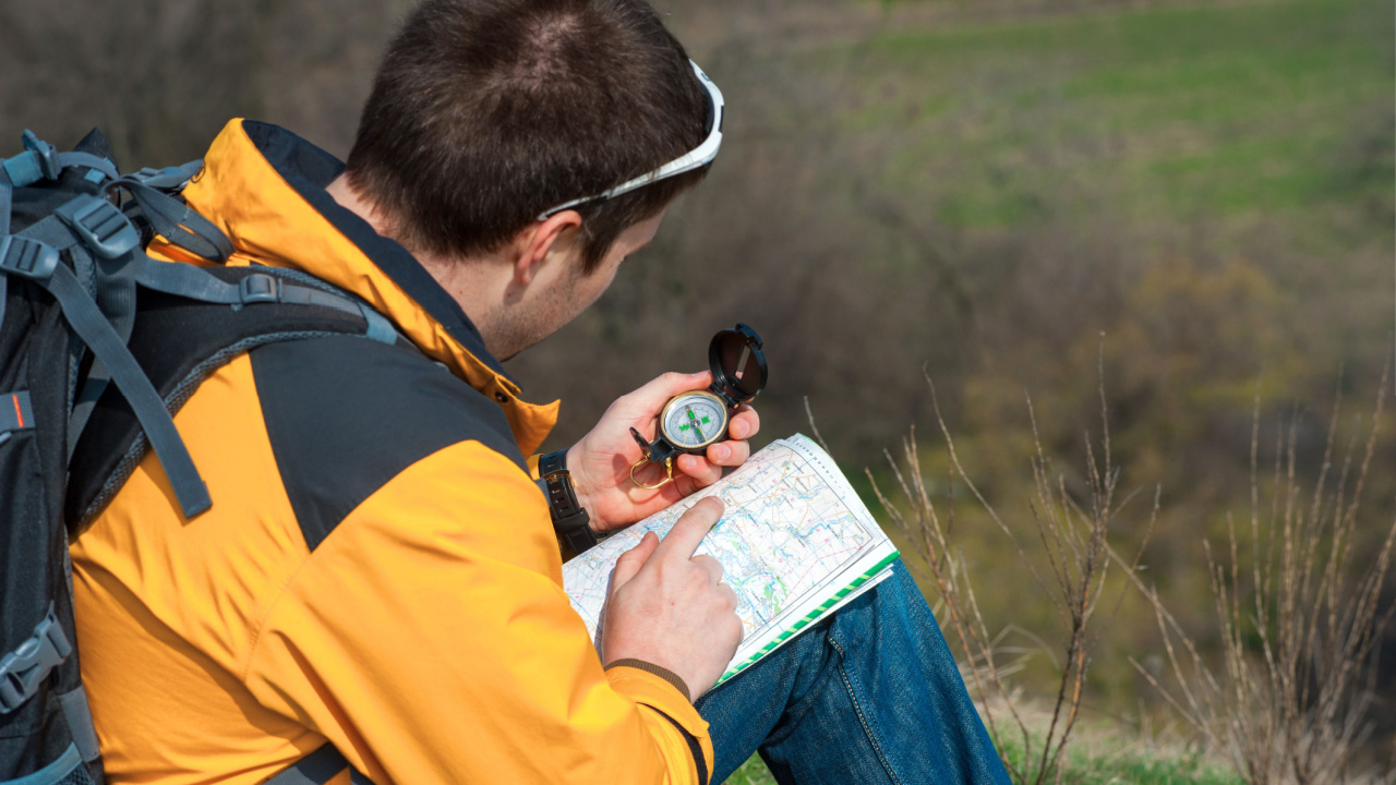 man reading compass and waterproof map