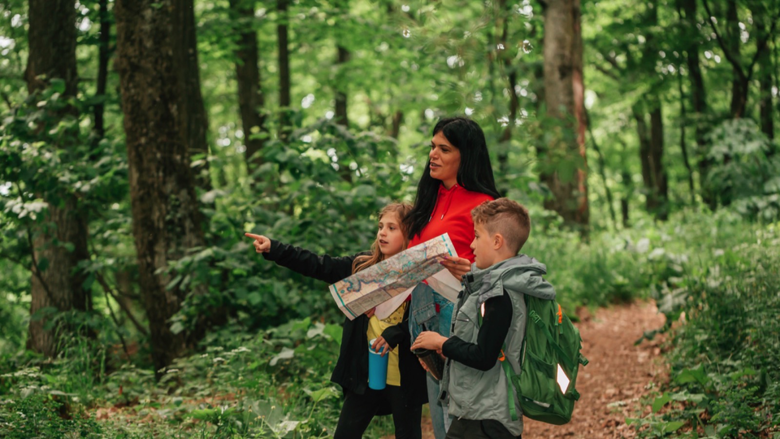 Mother teaching her kids to use map during hiking