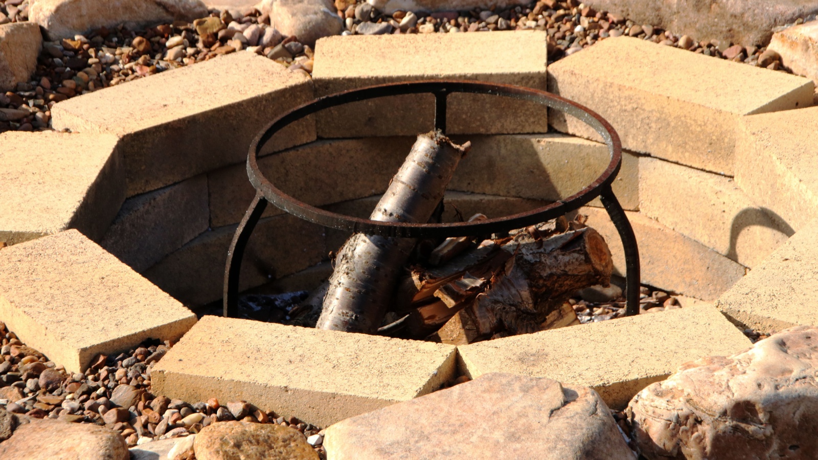 Fire pit with fuelwood surrounded by pebble in the summer garden