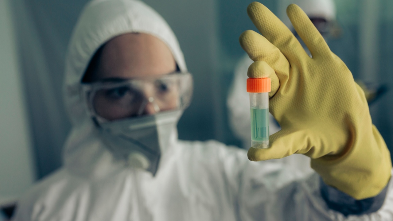 Female doctor with baceriological protective suit looking at an antidote vial for a dangerous virus