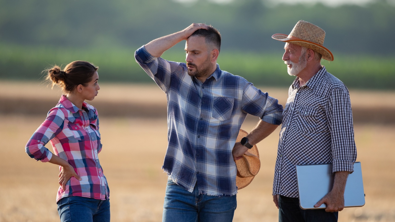 worried farmers standing in a field, man, woman, elderly man with a clipboard