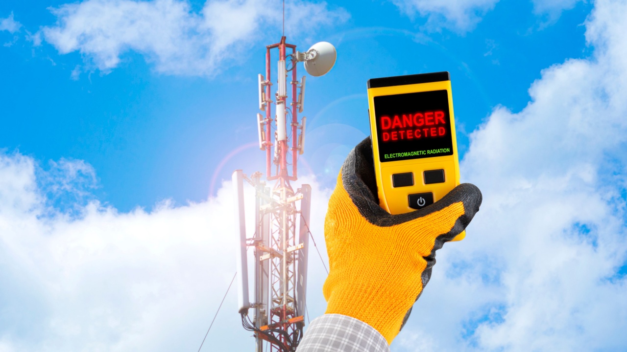 Measuring electromagnetic radiation from a cell tower. The device indicates hazardous radiation with text Danger. Influence of the electromagnetic field on humans concept.