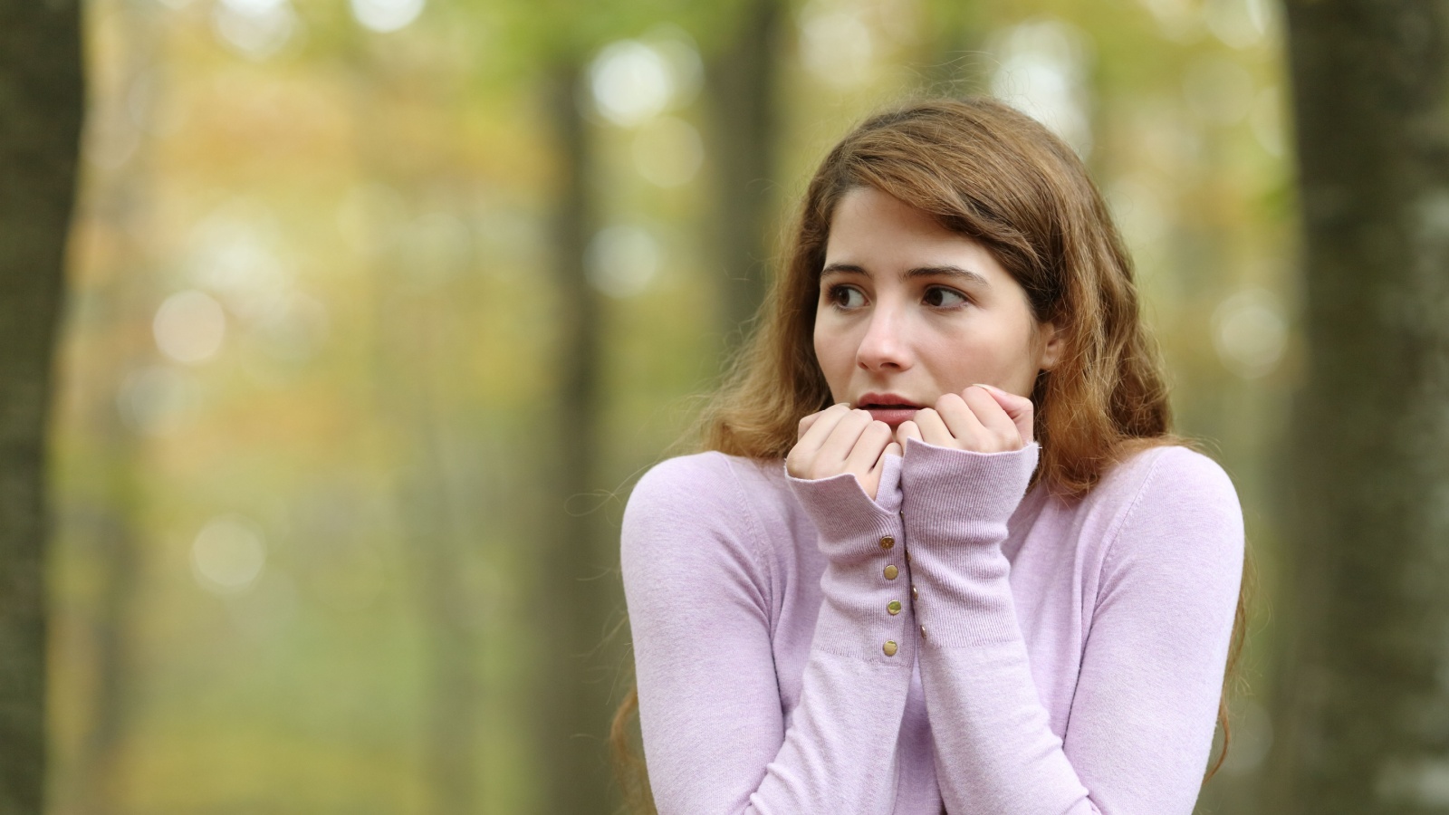 Scared woman looking at side walking alone in a park, potential threat