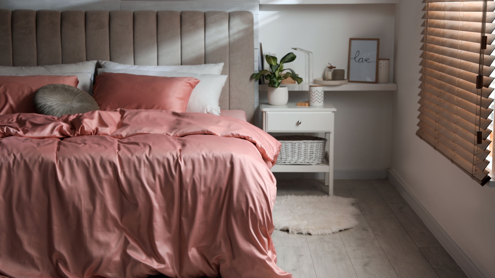 Bed with beautiful silky linens in stylish room interior