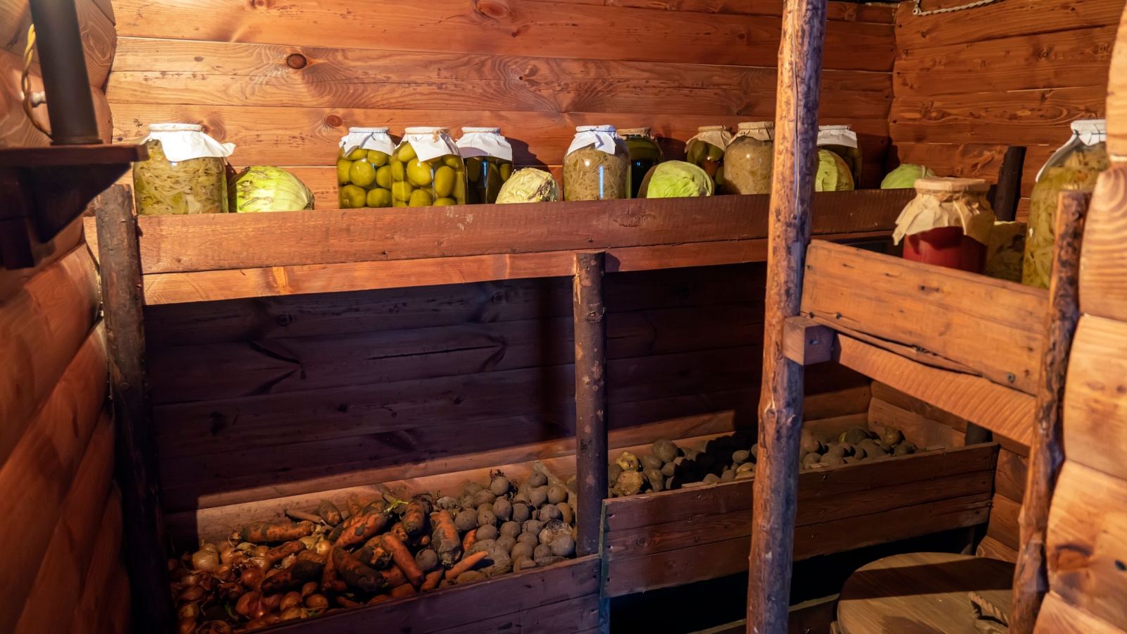 Preservation of vegetables in a warm cellar, basement for the winter period. Glass jars with pickled cucumbers on the shelf.