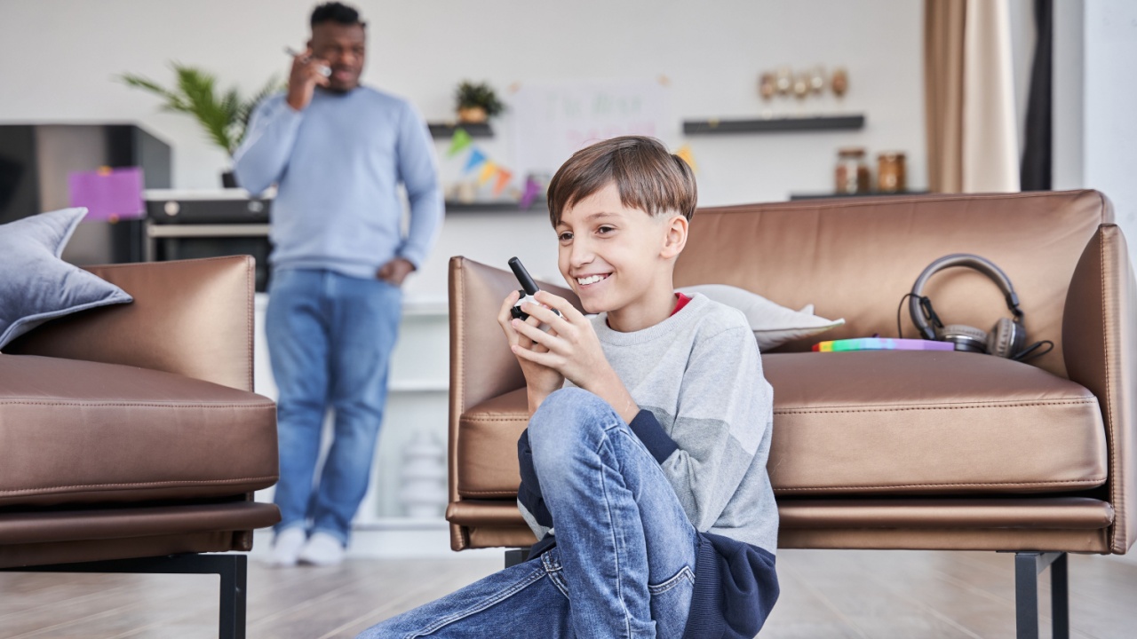 Boy sitting and talking with his father via walkie-talkie while spending time at the living room, communication