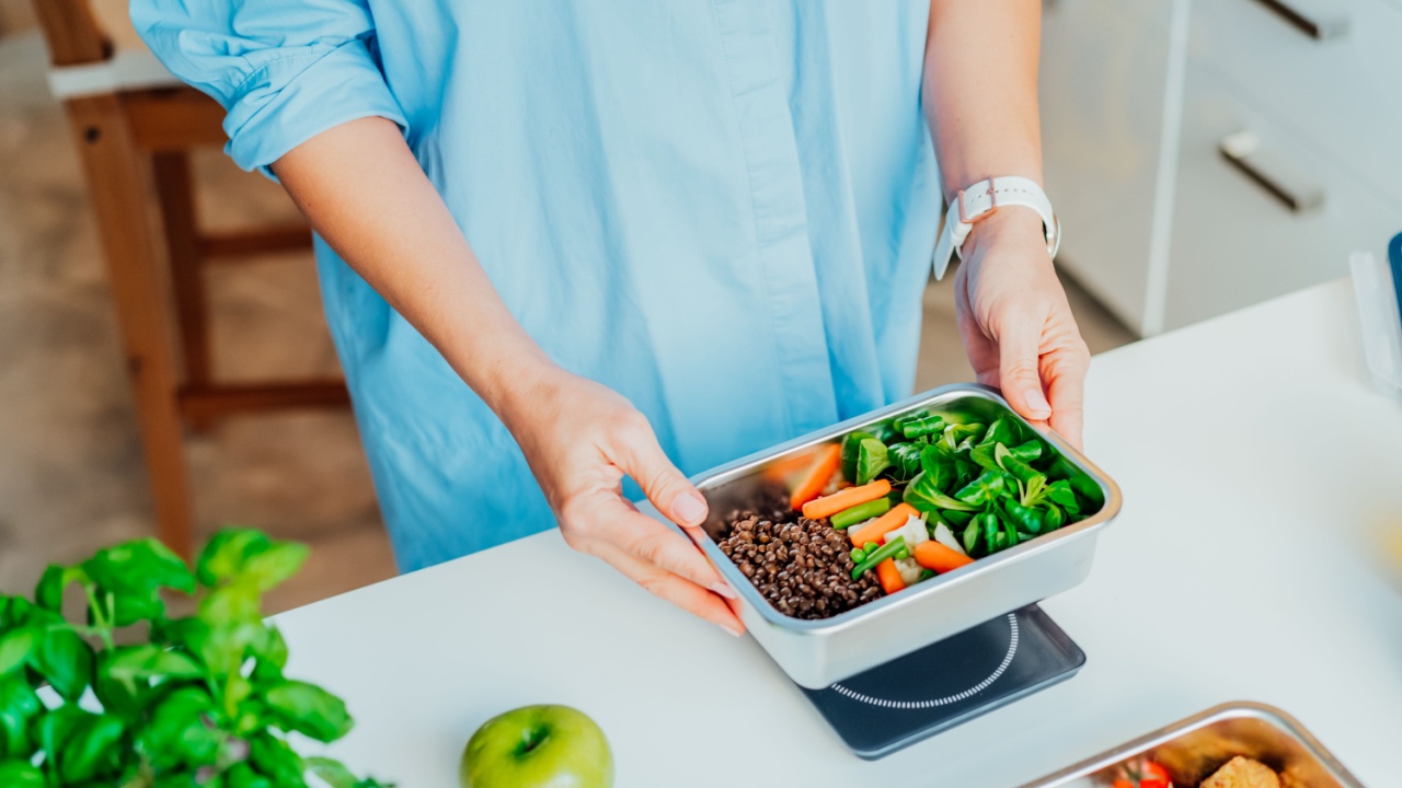 Healthy diet plan for weight loss, daily ready meal menu. Close up Woman weighing lunch box cooked in advance,ready to eat on kitchen scale. Balanced portion with healthy dish. food ration