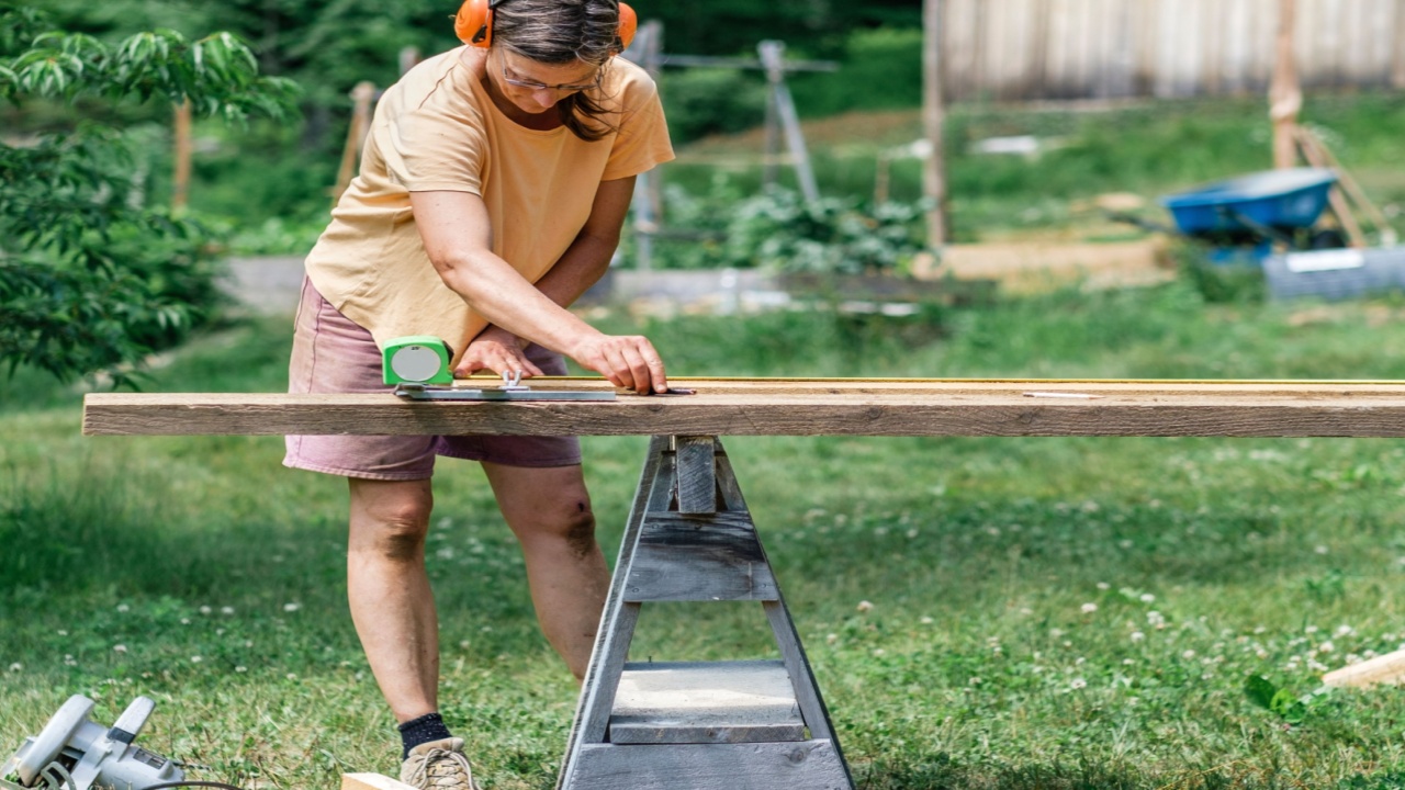 Older woman working on DIY wood work home construction project in backyard using tools