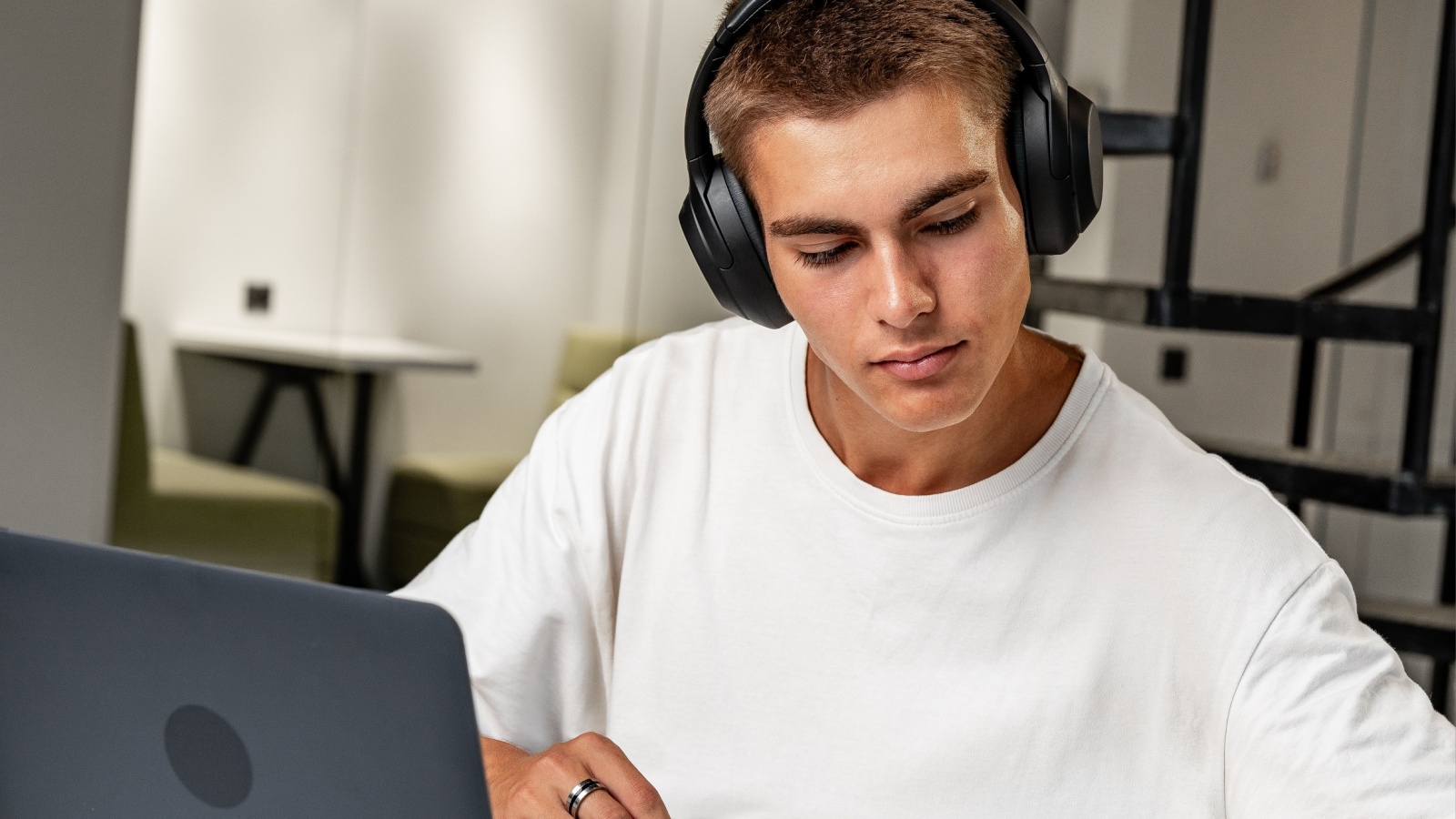 Young man wearing headphones while studying with laptop, learning