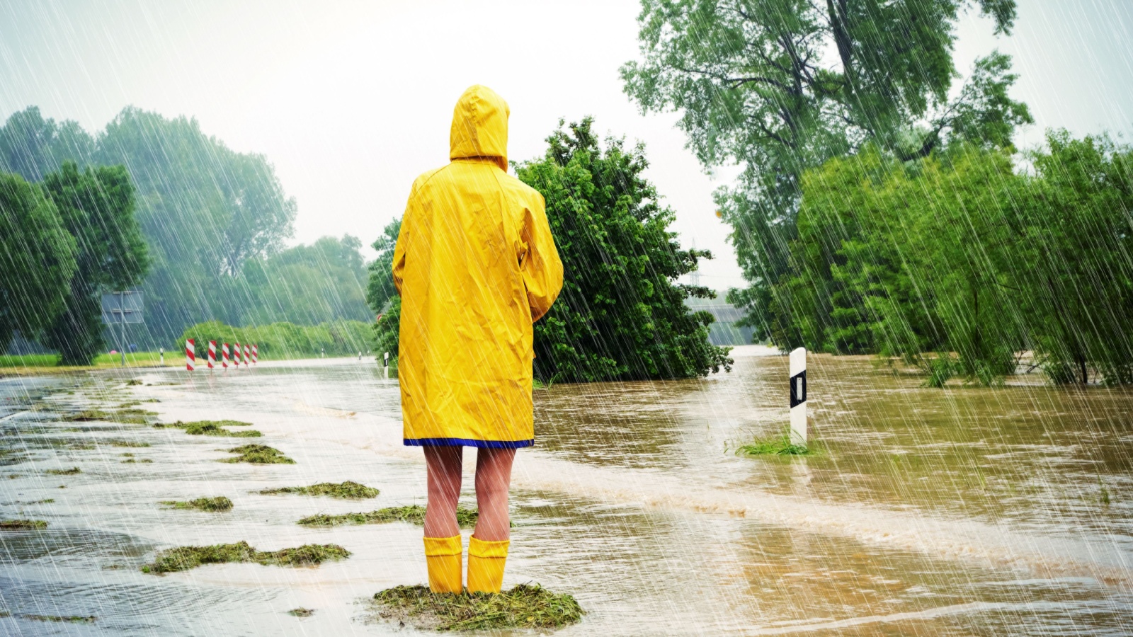 Woman standing in the rain wearing a raincoat and wellies