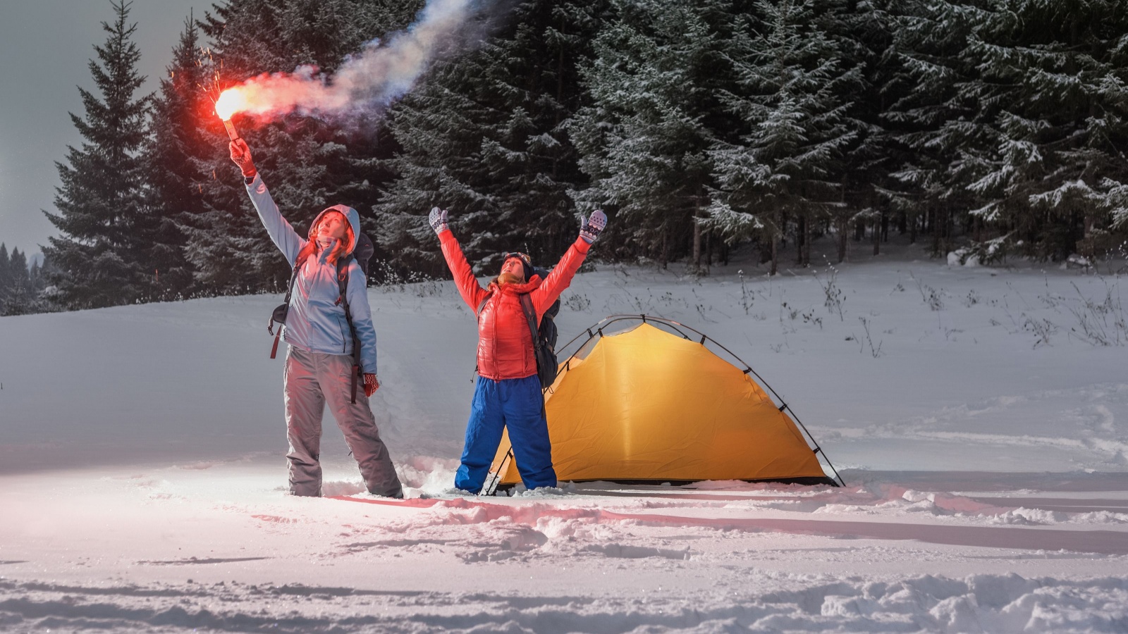 Two backpackers asking a help with rescue signal fire in a winter field