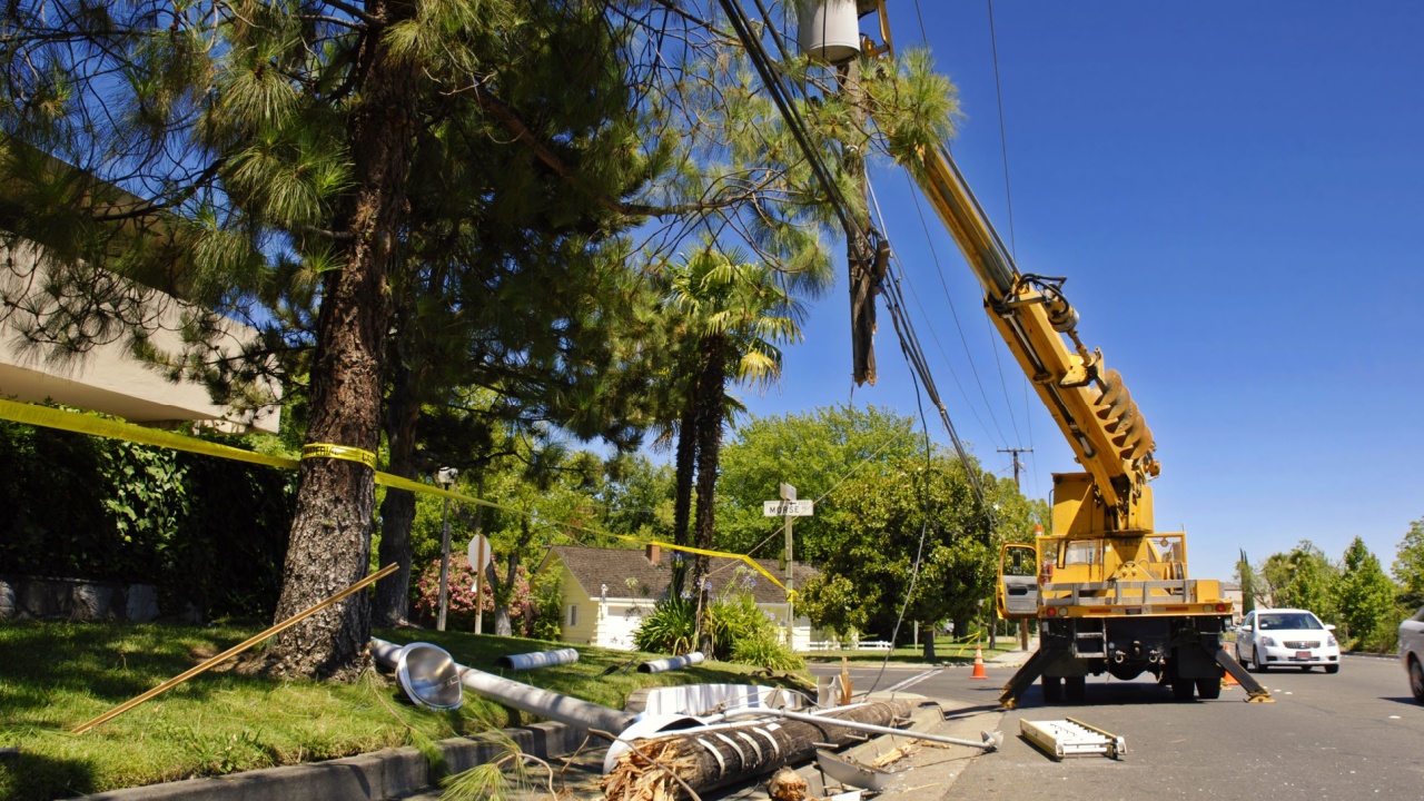 Utility truck lifts a severed power pole and lines after an accident