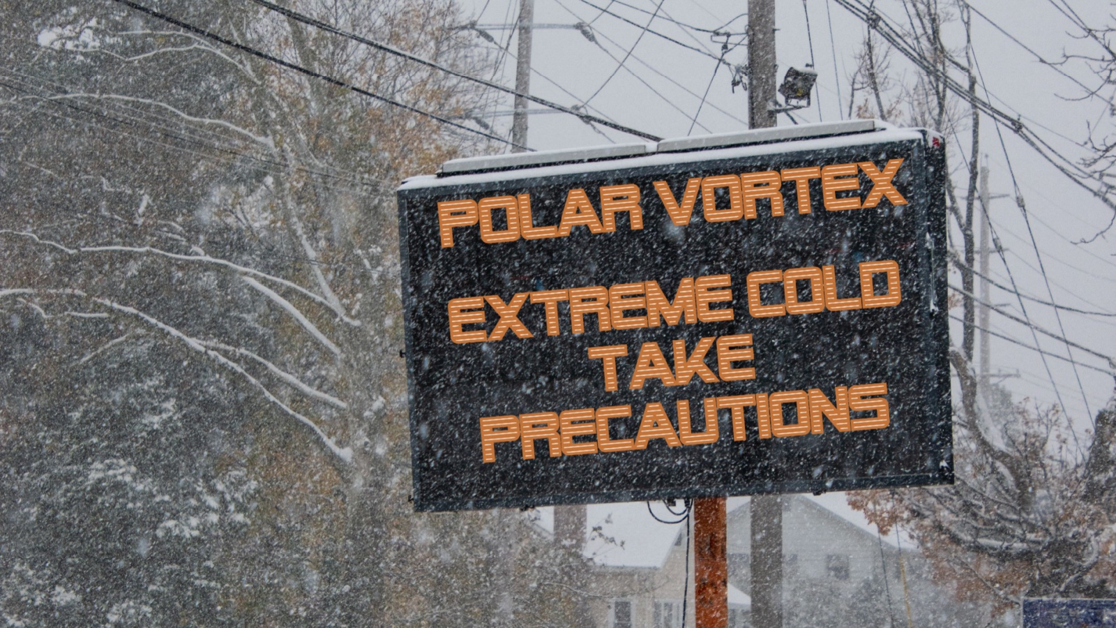 Electric road traffic mobile sign by the side of a snow covered road with snow falling warning of polar vortex, extreme cold take precautions