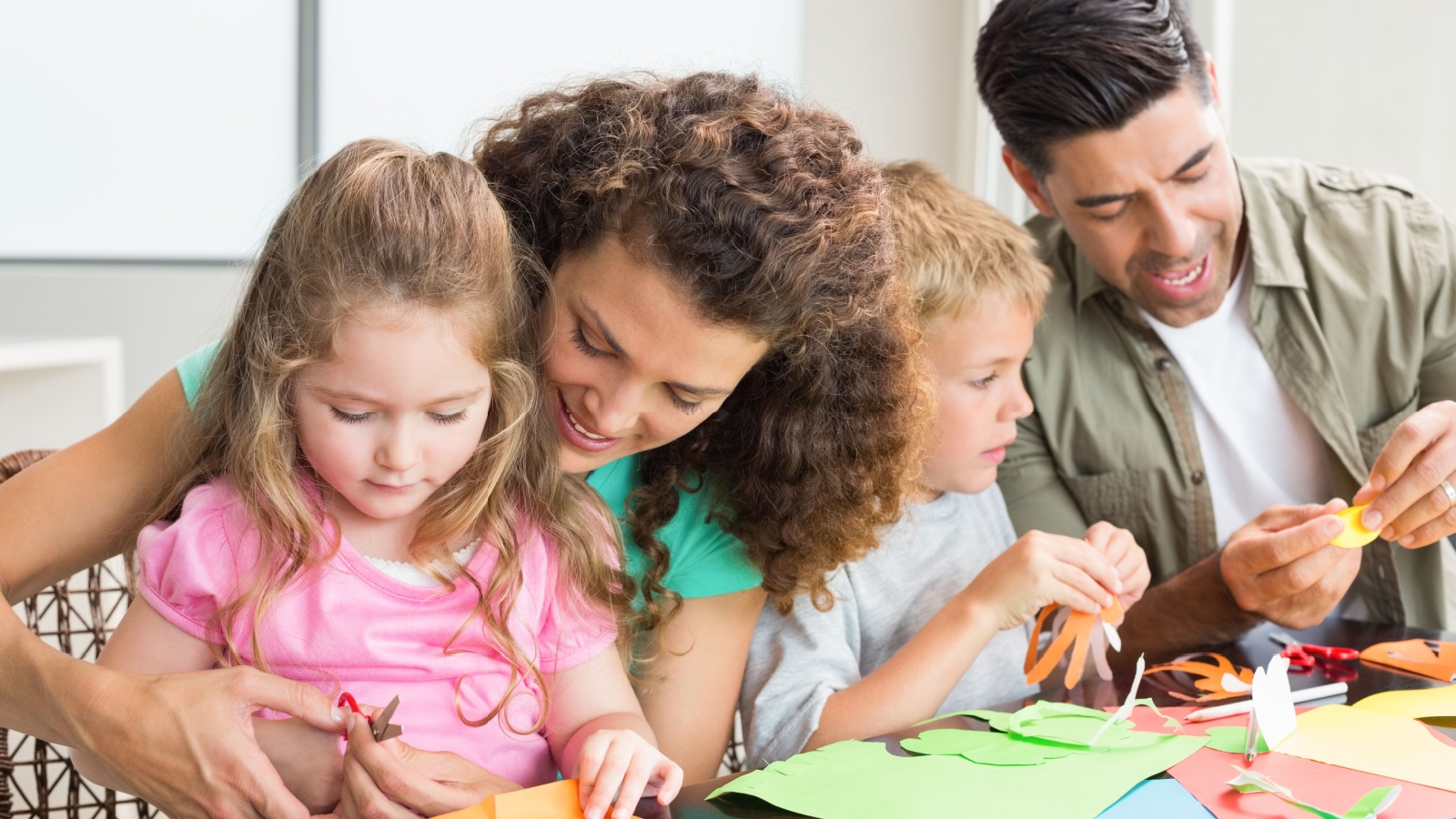 Cheerful family doing arts and crafts together at the table at home in kitchen