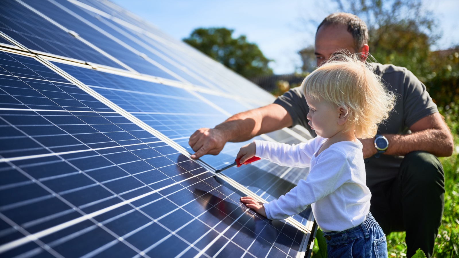 Man showing his small child the solar panels during sunny day. Father presenting to daughter modern energy resource. Little steps to alternative energy.