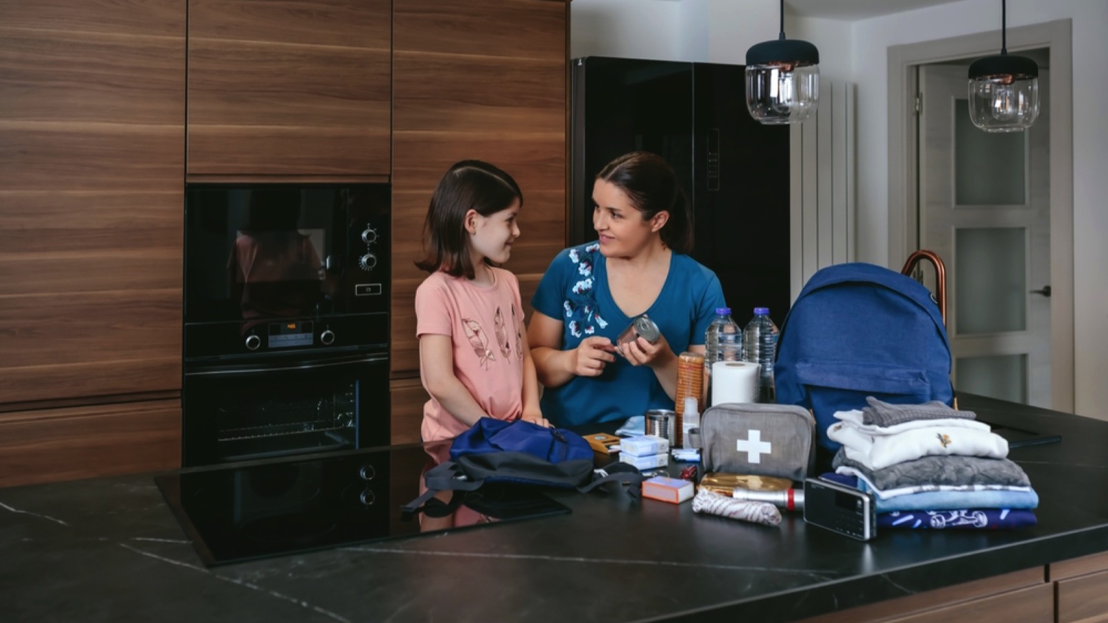 Mother explaining to her daughter how to prepare an emergency backpack