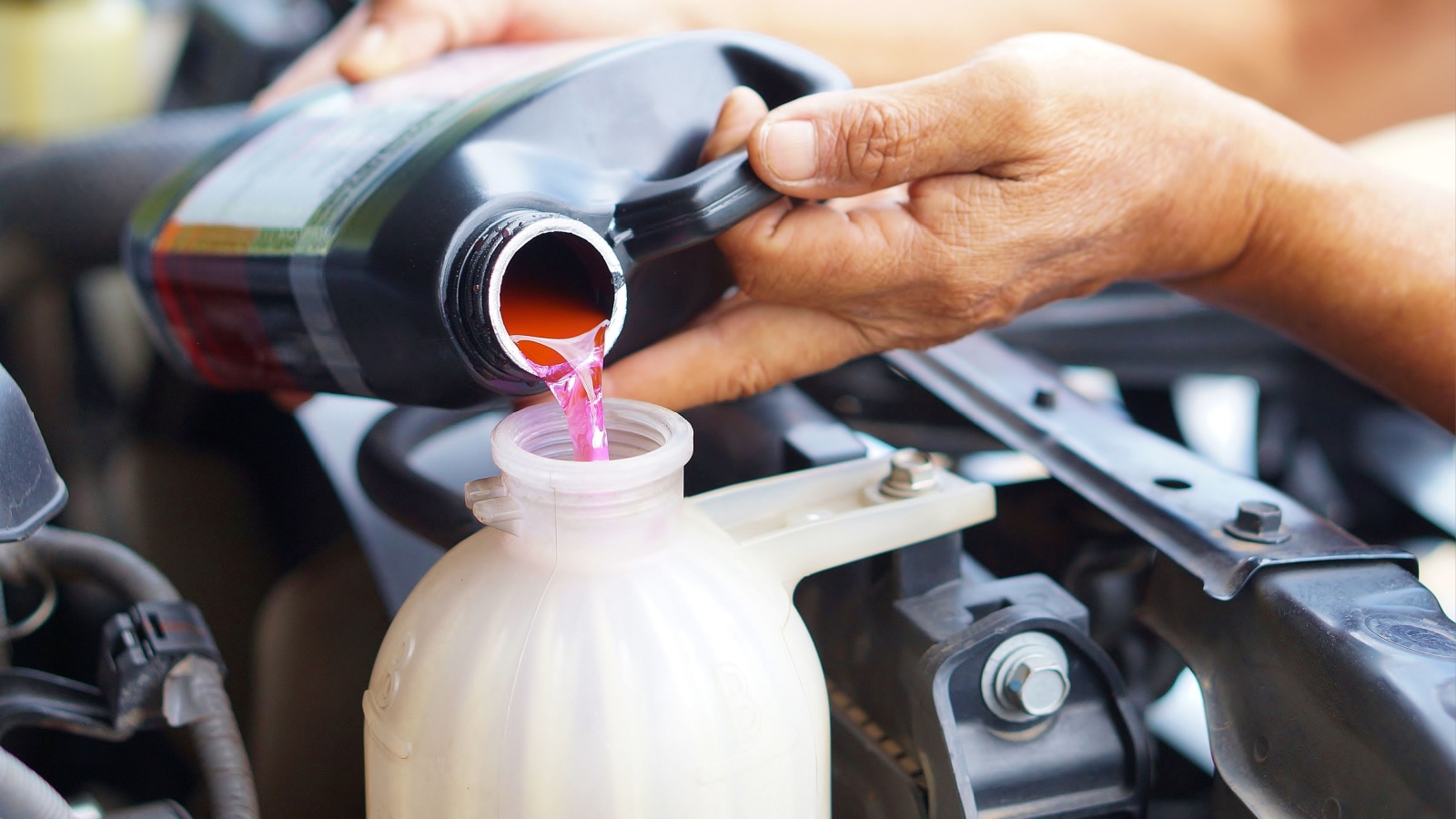 male hand filling car cooling system with coolant