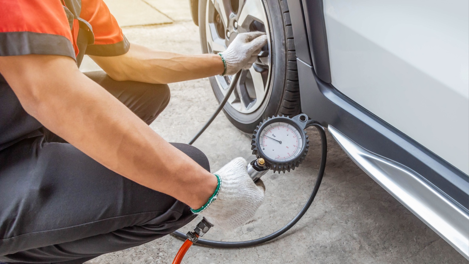 The man inflating put air into the tyre and checking air pressure with gauge pressure in service station