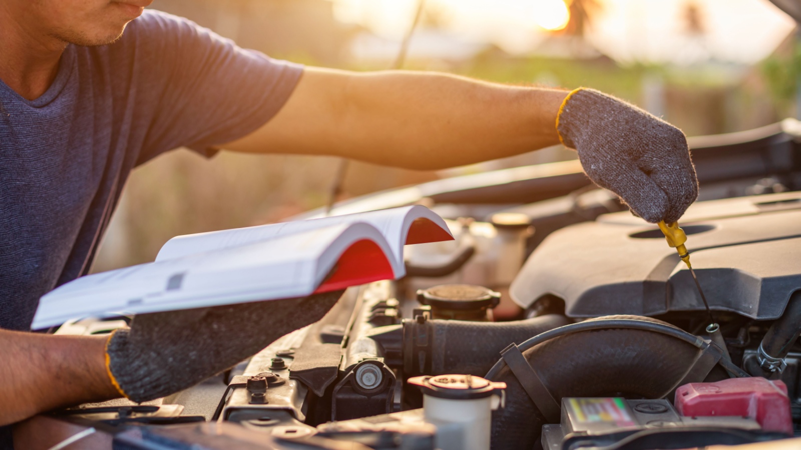 Asian man holding and reading the car user manual or user instruction to checking or fixing engine of modern car. Car maintenance or service 