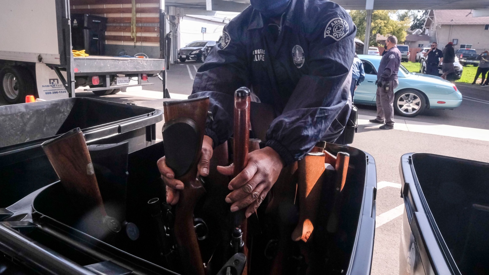 A Los Angeles Police Gun Unit officer drops off rifles traded in by people during an anonymous gun-buyback event in Los Angeles