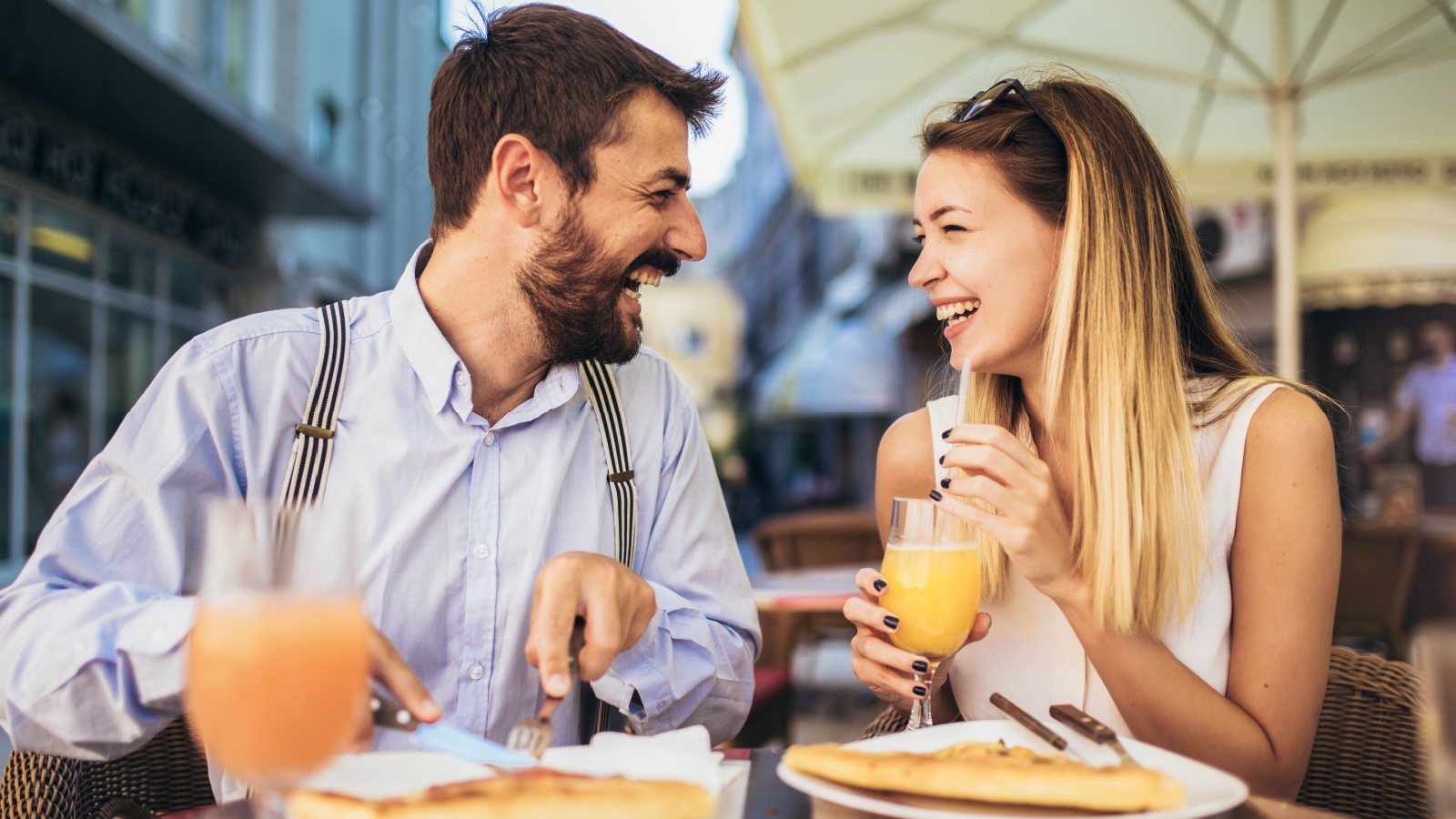 happy young couple having good time in cafe restaurant. They are smiling and eating a pizza.