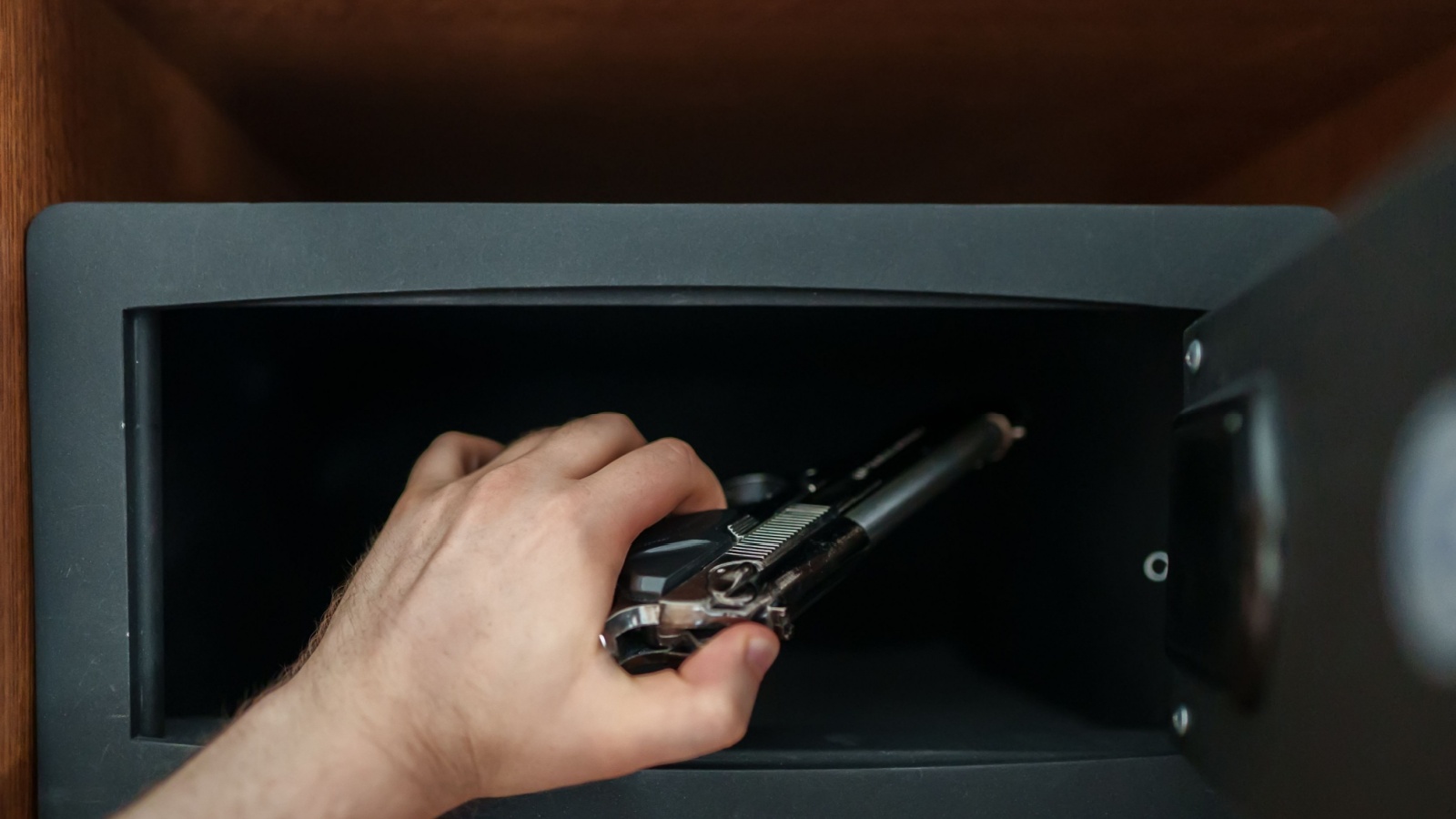 Man puts the weapon in the safe.