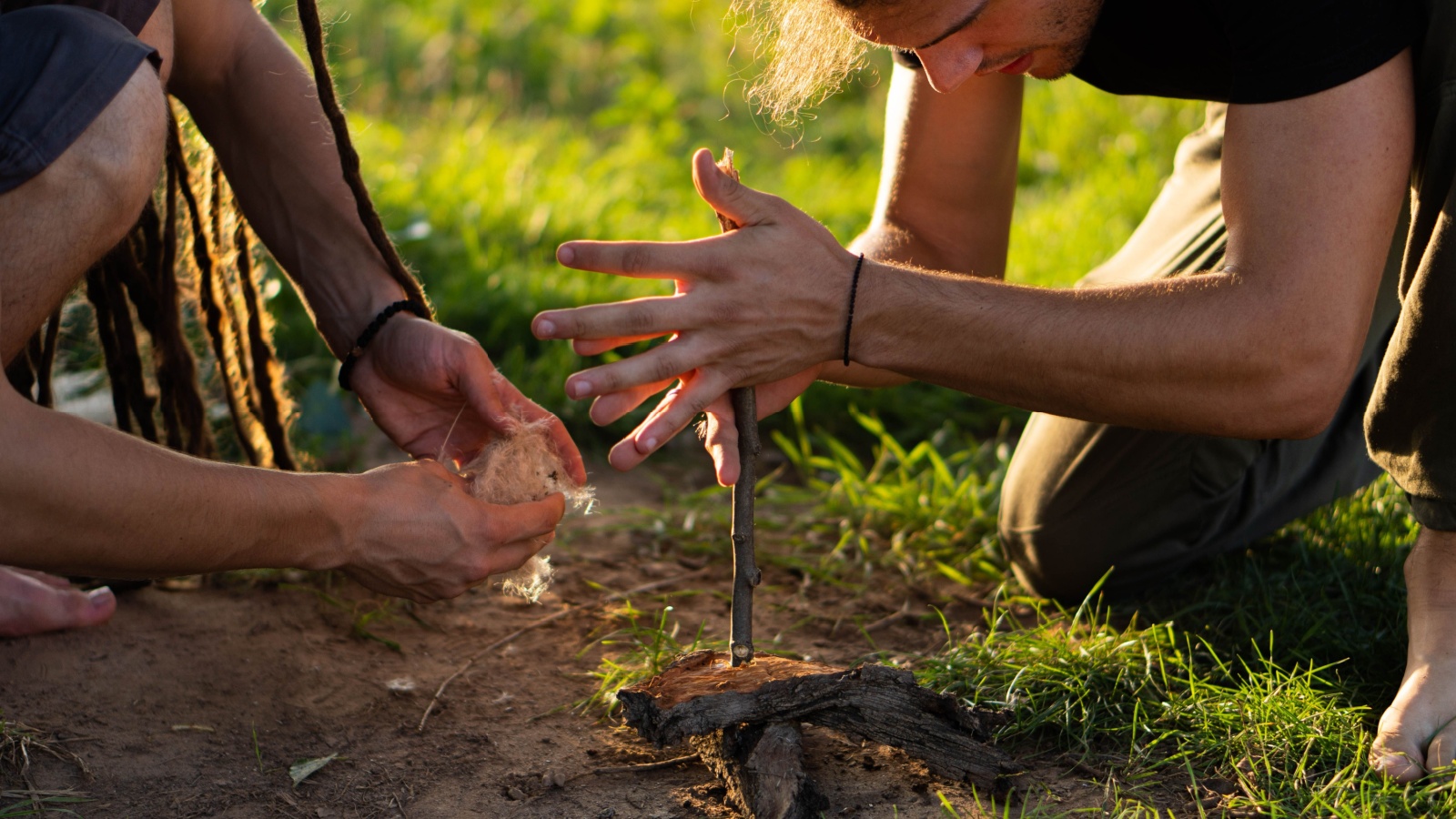 Two boys trying to make a fire with hand-drill method.