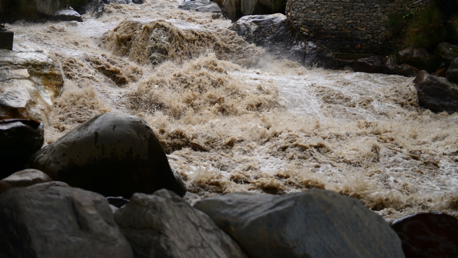 High-pressure flood water in mountain river tributary, caused by global warming, melting glaciers, and torrential rains.