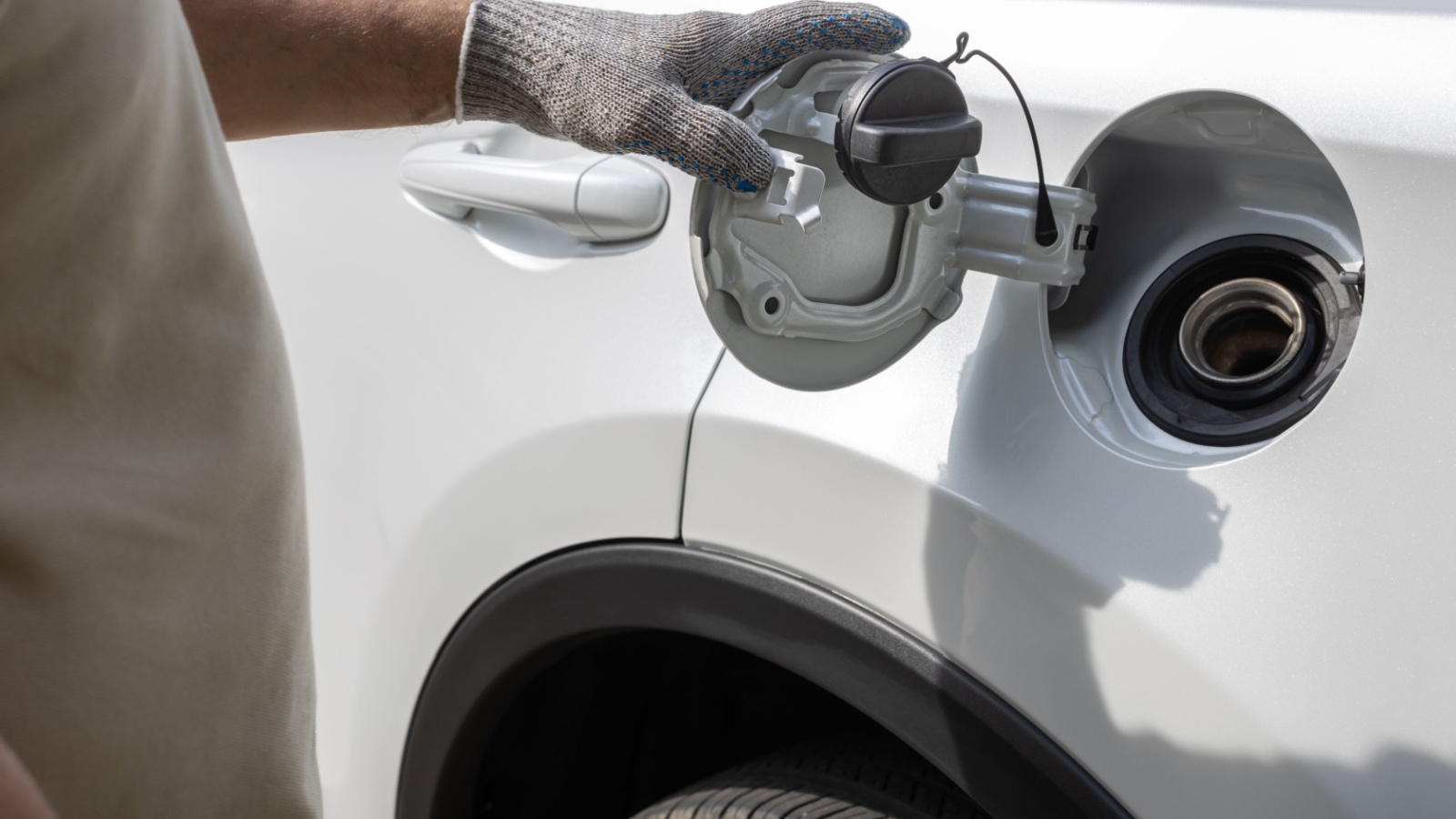 man opens the hatch of the gas tank of the car. Gloved hand opens gas tank