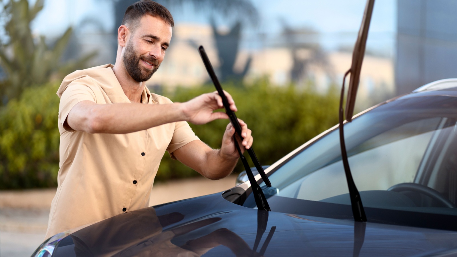 man replace windshield wipers on car standing outdoors. Car service 