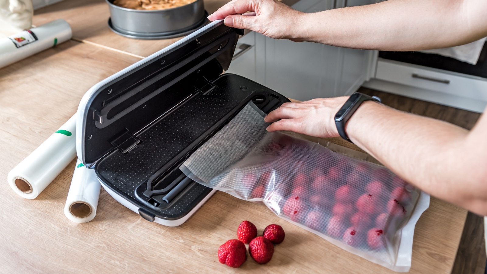 Woman use vacuum sealer packing machine for long-term storage of products. Vacuum strawberries packaging for long-term storage.