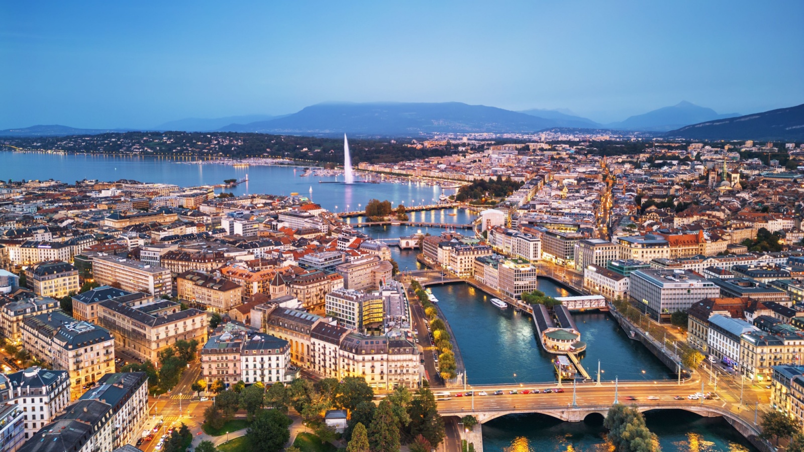 Geneva, Switzerland skyline view towards the Jet d'Eau fountain in Lake Geneva at twilight.