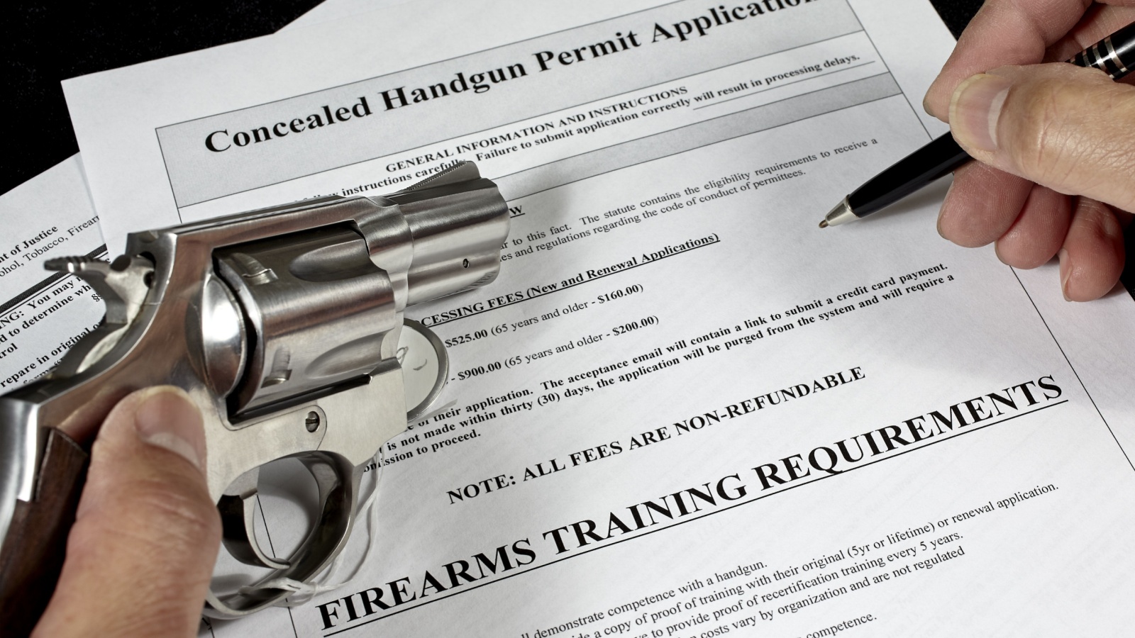 man with handgun firearm pistol and concealed carry permit application