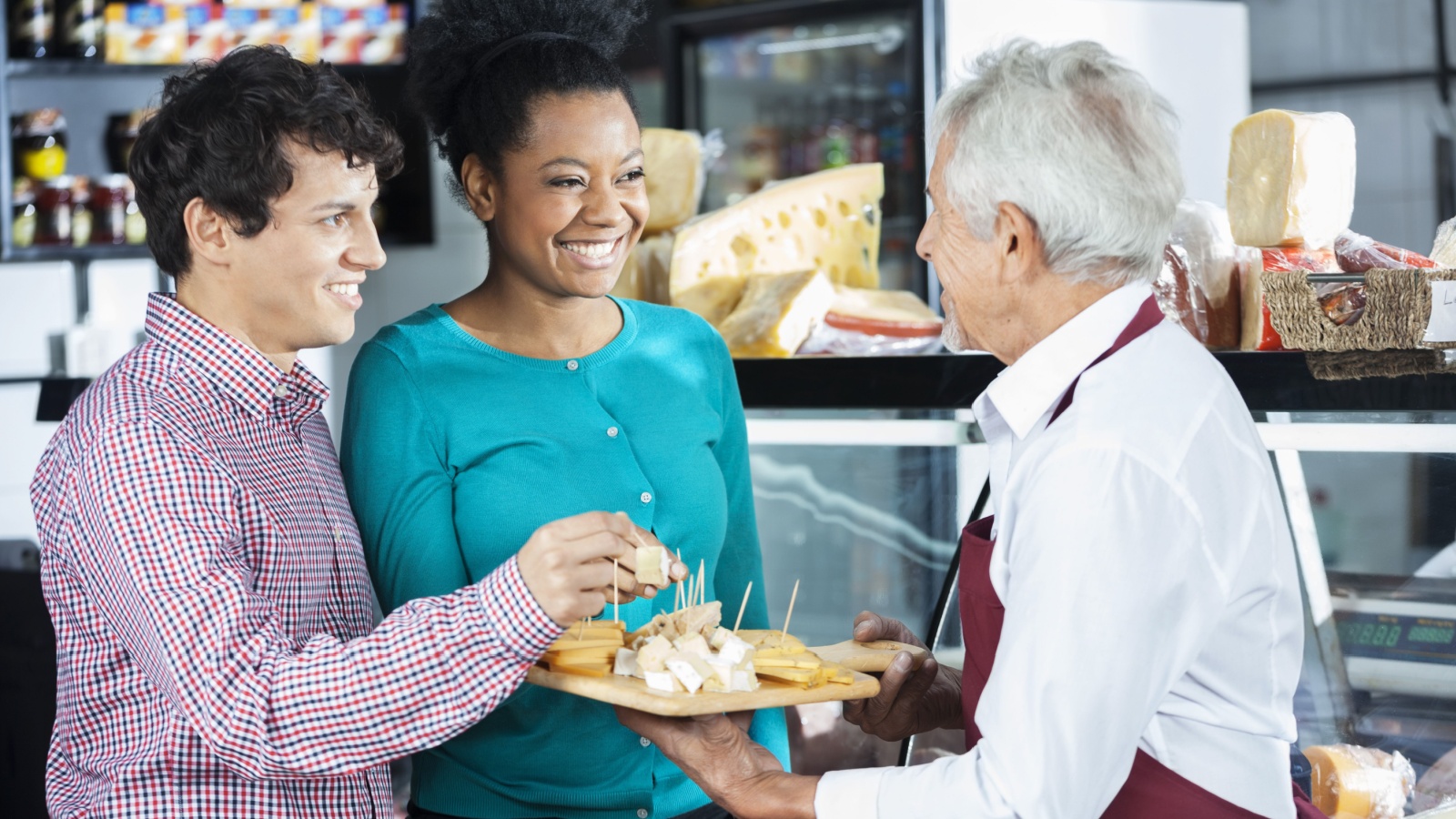 Salesman Offering Cheese Samples To Customers In Shop