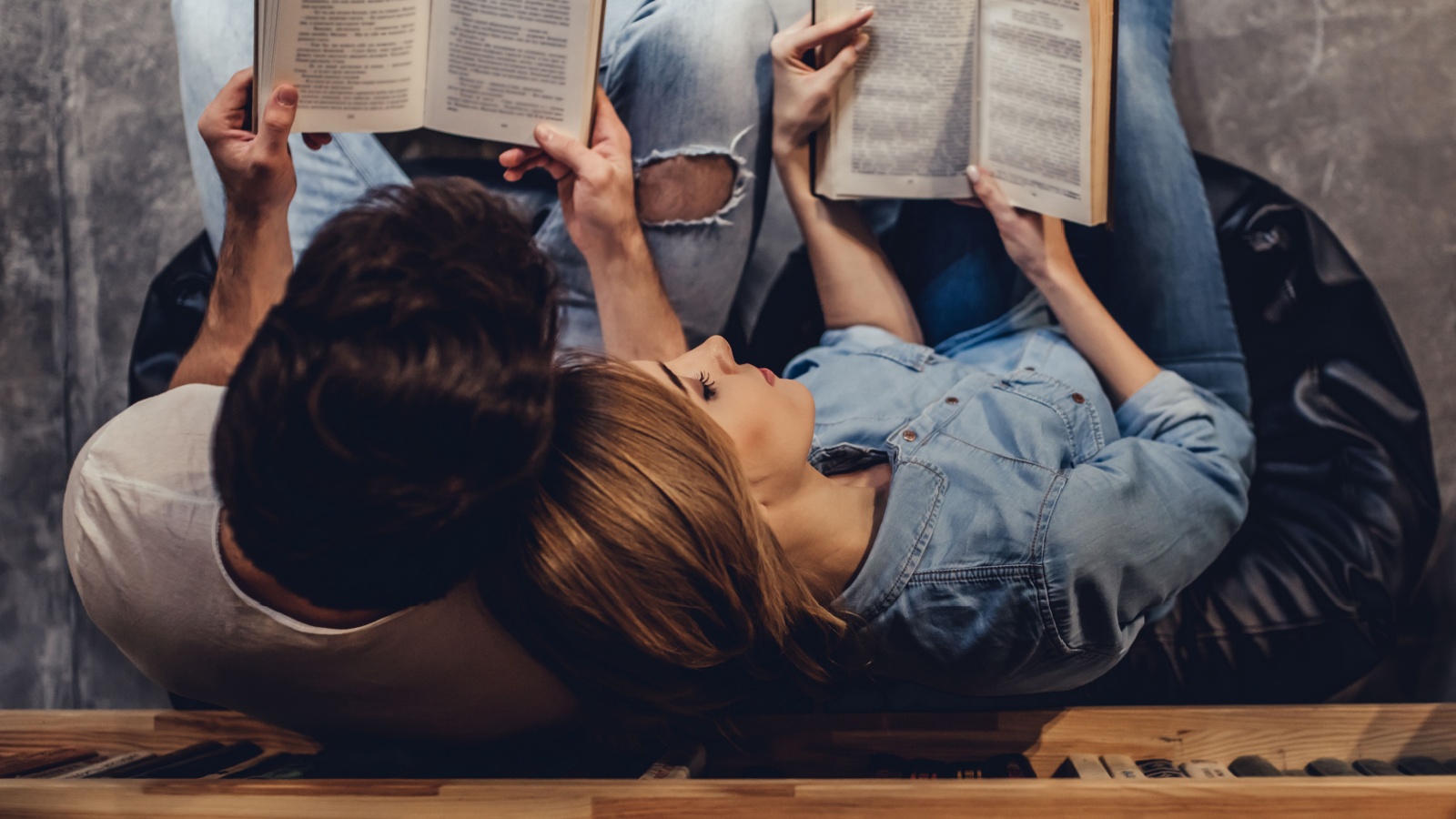 Young people are spending time together. Romantic couple is kissing while reading book.