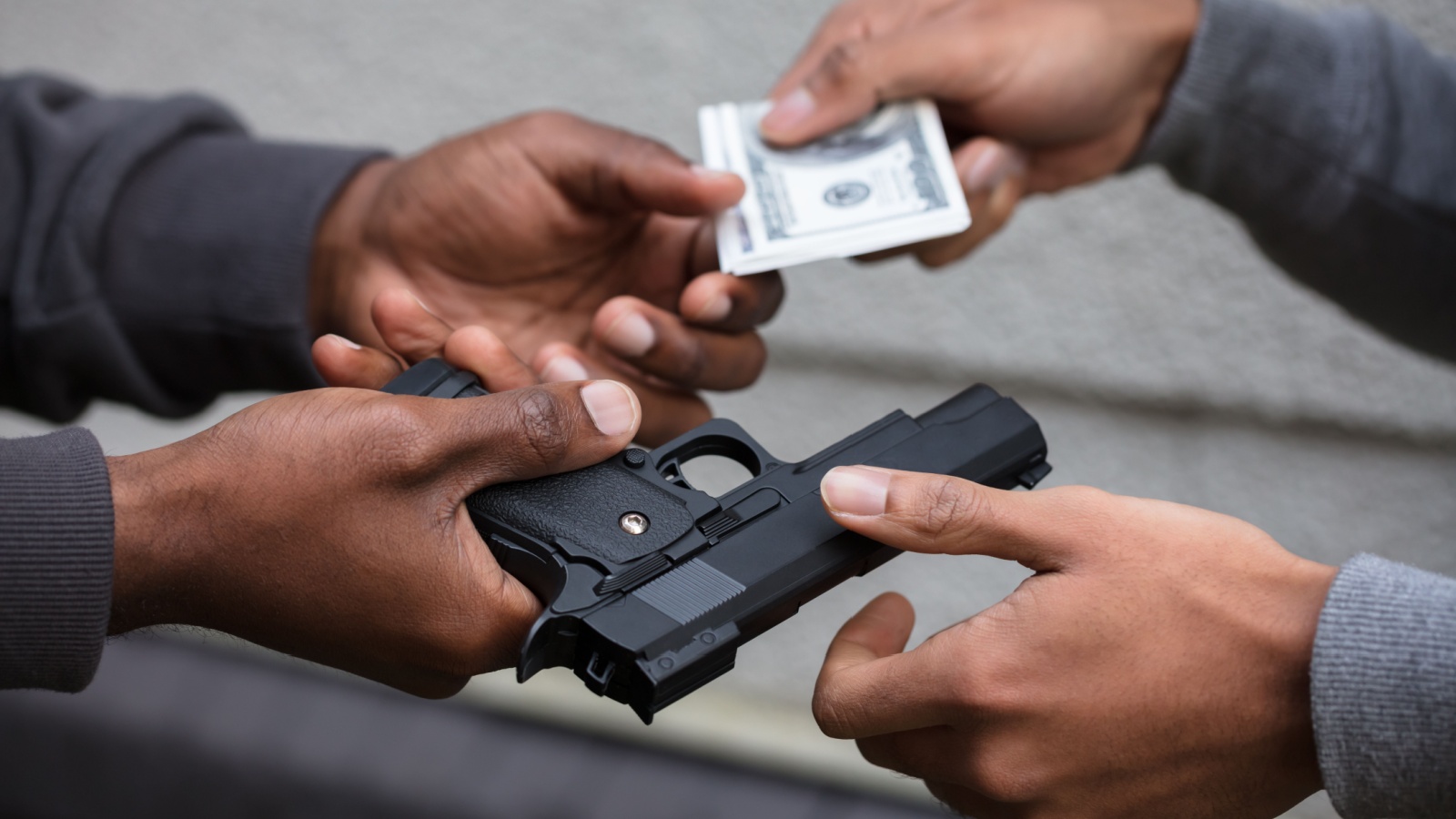 Two Hands Exchanging Black Handgun For Banknote