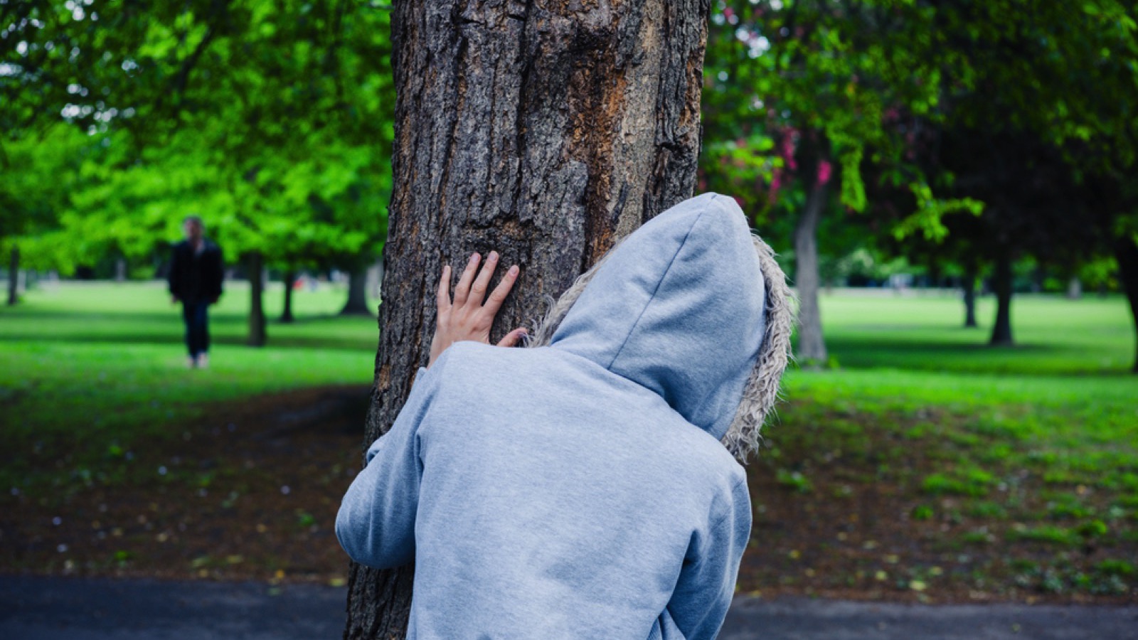 Woman hiding behind tree and walking